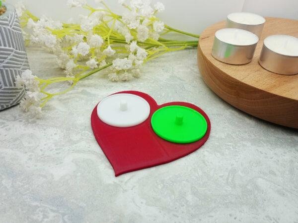 The Philips electric toothbrush holder for two people is displayed with the red base and one yellow and one yellow insert. Standard size tealights are included to give a sense of scale. An Philips electric toothbrush is also included in the image to give a sense of scale and how it looks with the toothbrush mounted on the holder. The modern yet classic look of the love heart in this playful setting is on display.