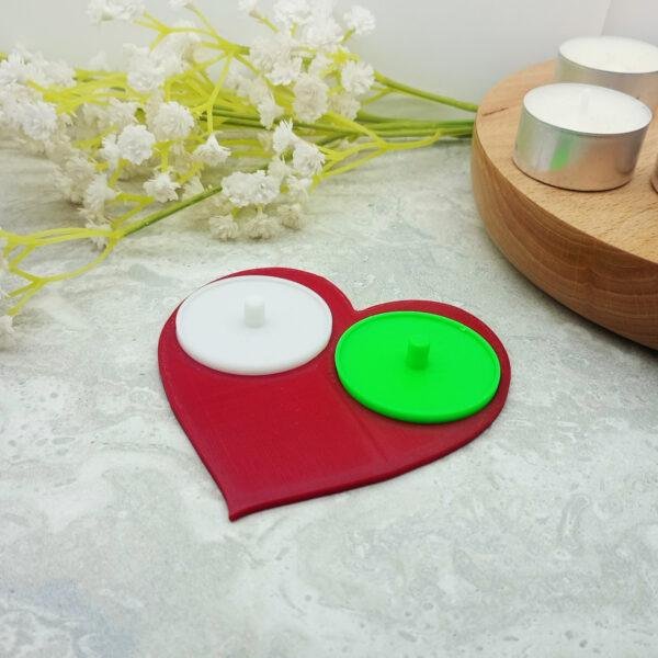 The Philips electric toothbrush holder for two people is displayed with the red base and one yellow and one yellow insert. Standard size tealights are included to give a sense of scale. An Philips electric toothbrush is also included in the image to give a sense of scale and how it looks with the toothbrush mounted on the holder. The modern yet classic look of the love heart in this playful setting is on display.